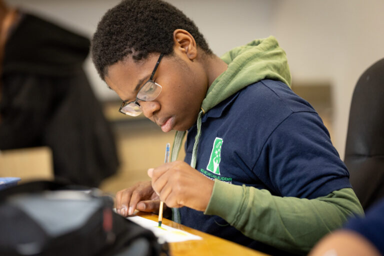Young student focused on creative painting activity in a supportive educational classroom setting.