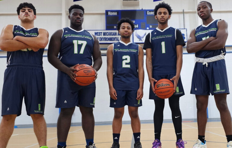 West Michigan Academy basketball team poses confidently on the court, showcasing unity and athleticism.
