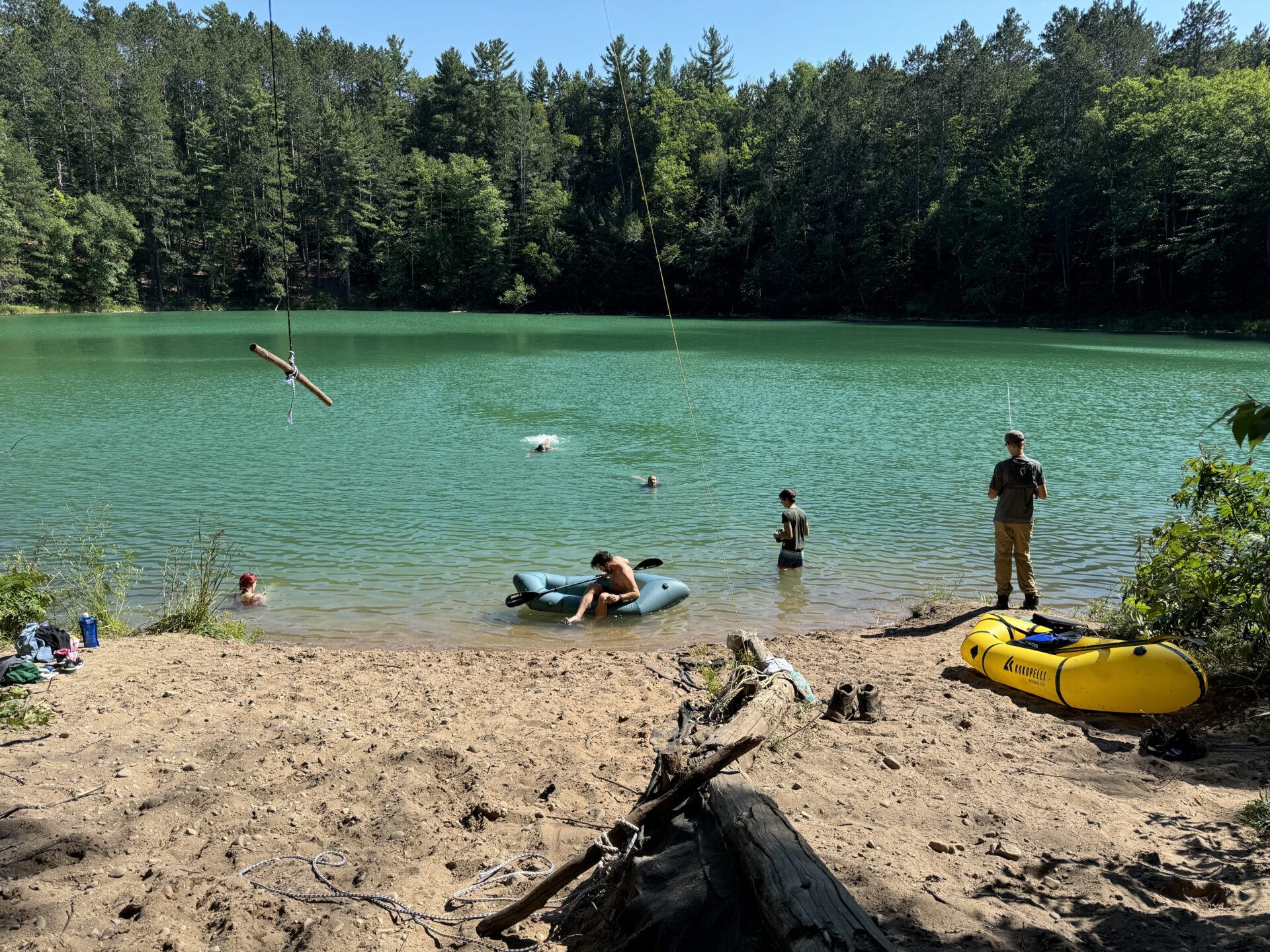 Vibrant lake scene with turquoise water, sandy shore, and people enjoying summer activities.