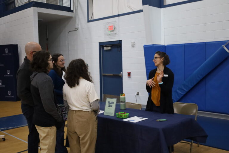 Engaged community event at a gym sharing insights about Inland Seas programs and activities.