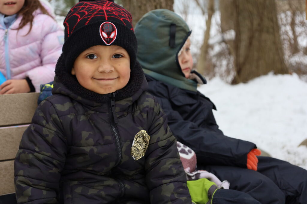 Boy in camouflage jacket enjoys winter play in snowy landscape with friends.