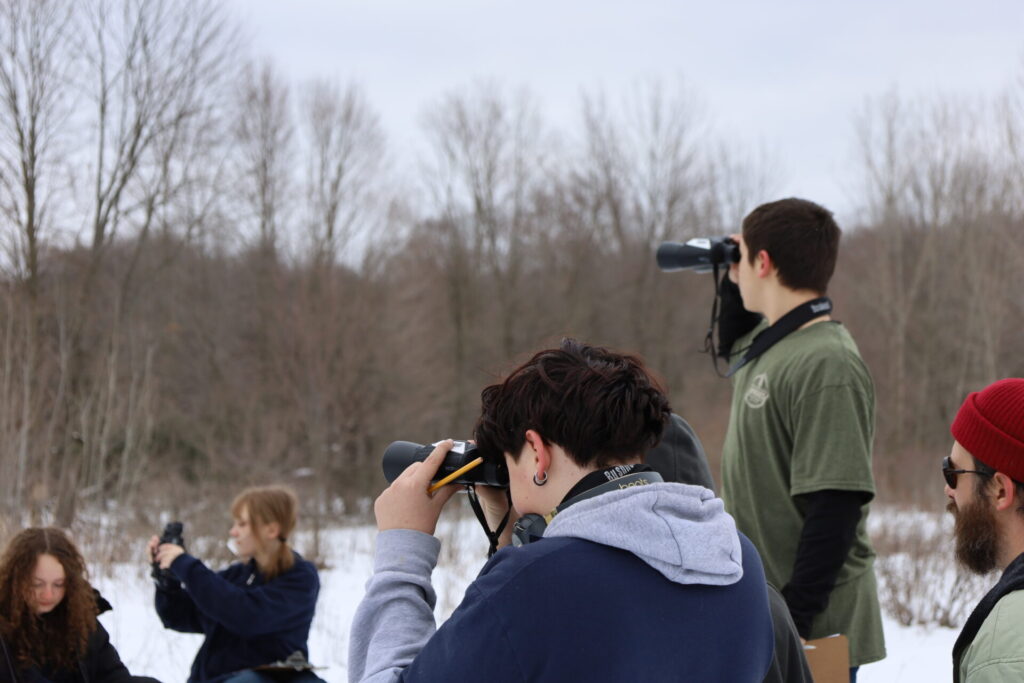 Young photographers capture winter landscapes in a snowy outdoor setting, showcasing their creativity.